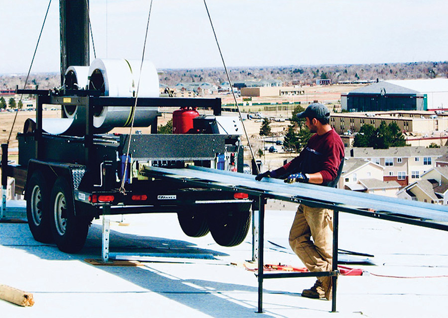 man installing metal roofing that is help on trailer 