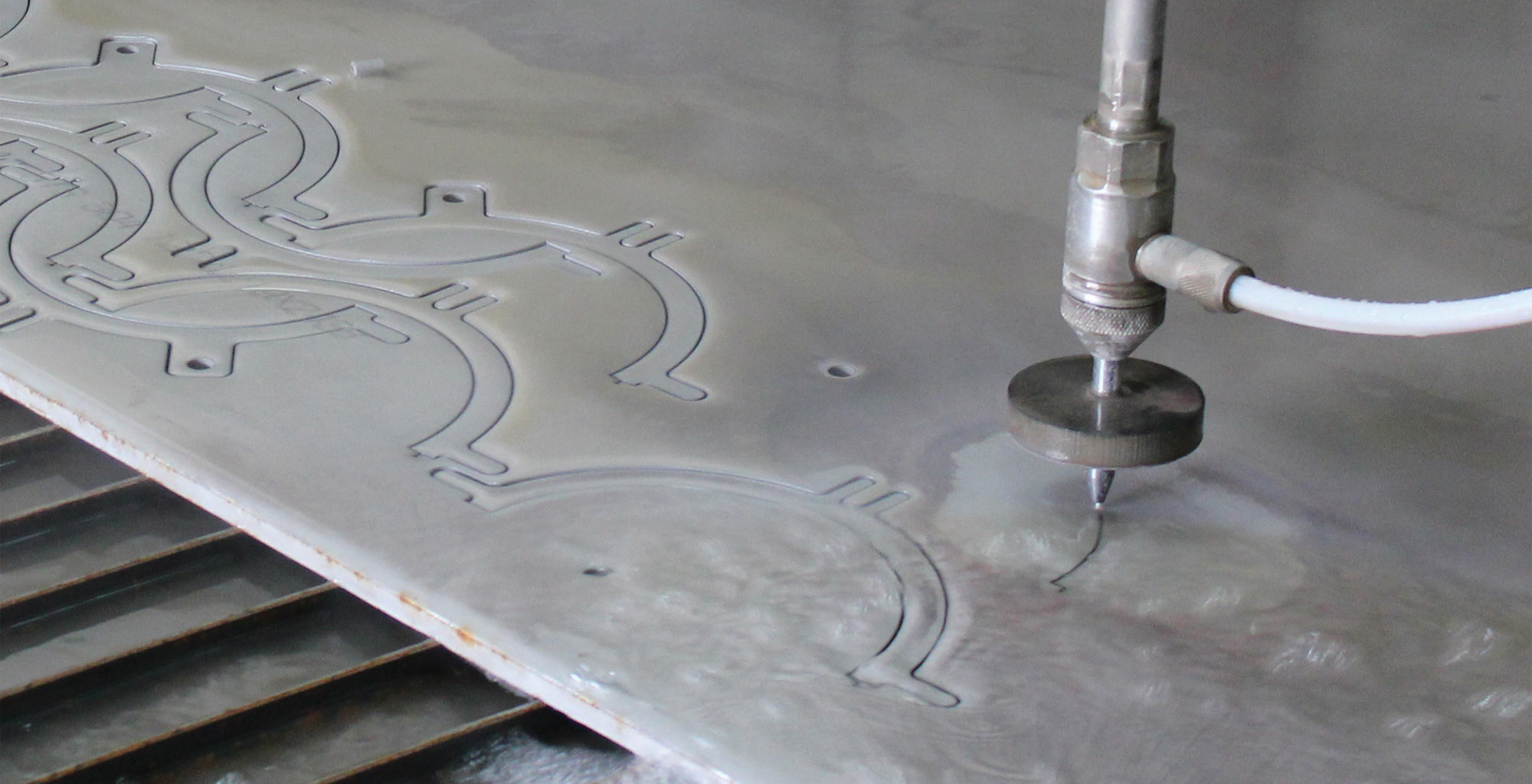 close view of a MultiCam waterjet cutting steel nested parts