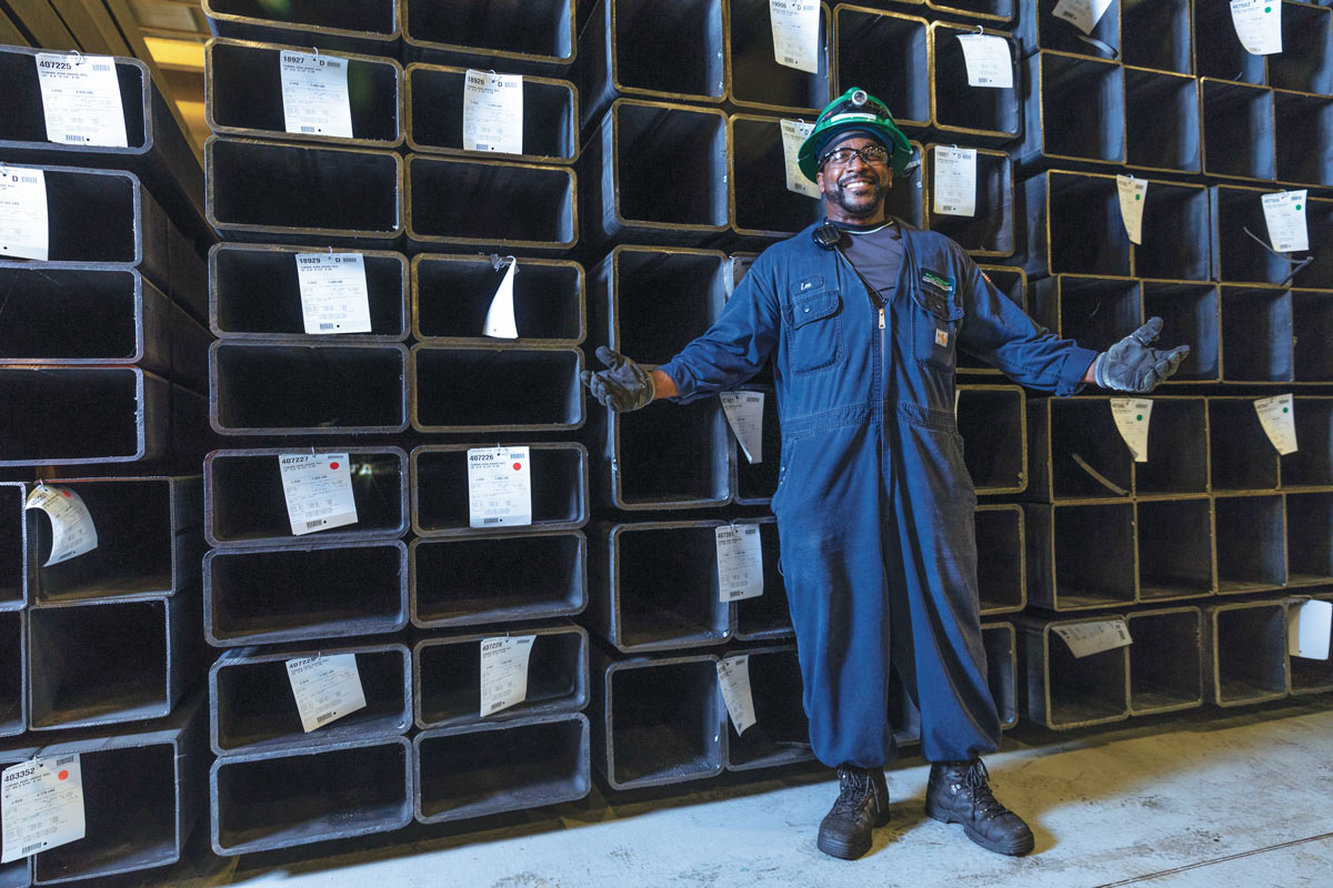 Nucor employee posing happily in front of steel storage